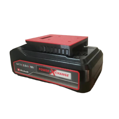 A black and red Einhell 18V PowerXChange Lithium-ion battery resting on a brown cardboard box in an indoor setting.