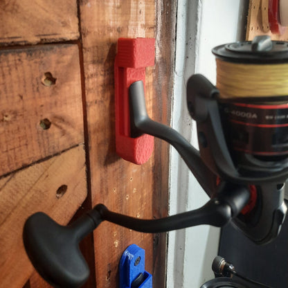 Fishing reel attached to a wooden surface with a red tool mount