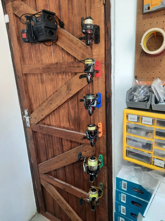 Wooden door with fishing reels attached, next to a pegboard with tools and supplies.