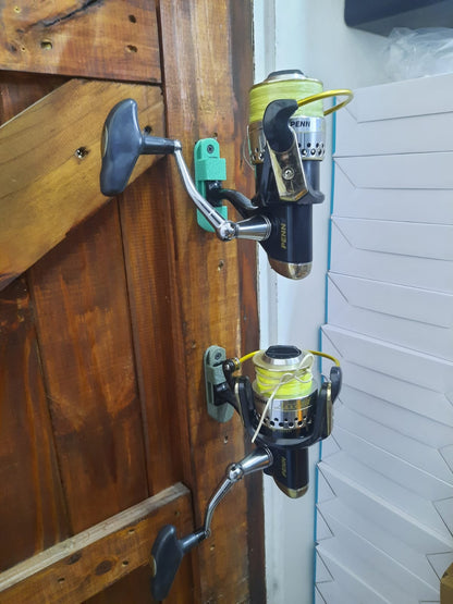 Two fishing reels attached to a wooden surface with a white wall in the background.