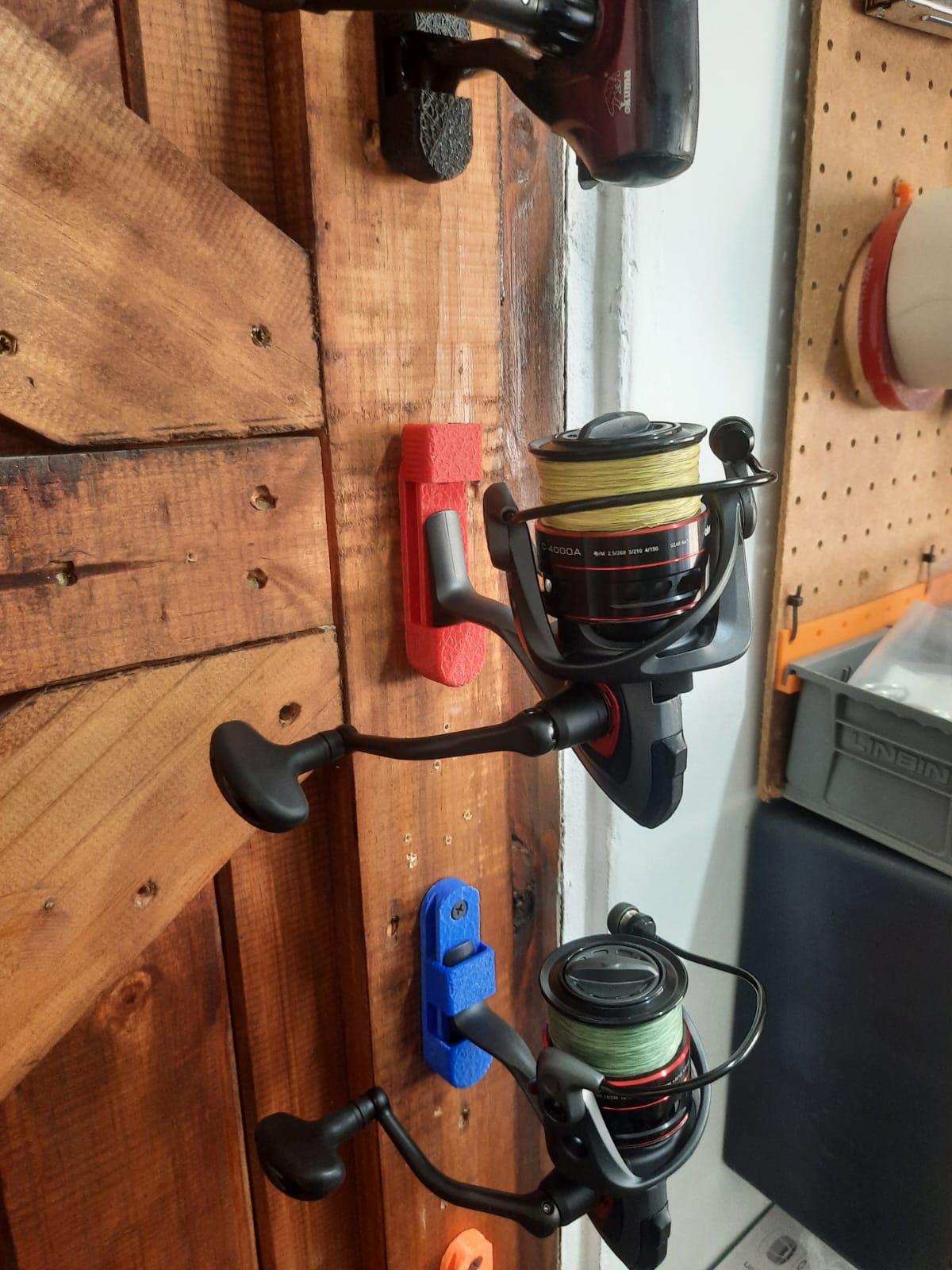 Fishing reels attached to a wooden door with pegboard background